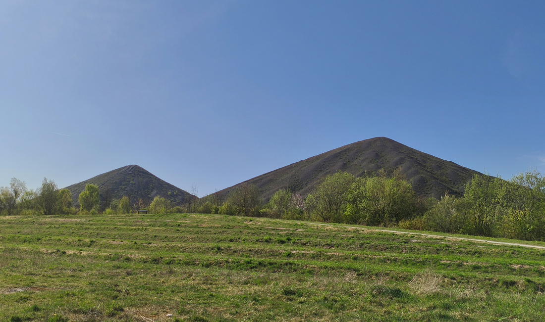 Photographie sur laquelle on voit, au loin, deux montagnes de terre, sans autre forme de végétation que de l’herbe. Au premier plan, des plaines, d’où la photographie est probablement prise.
